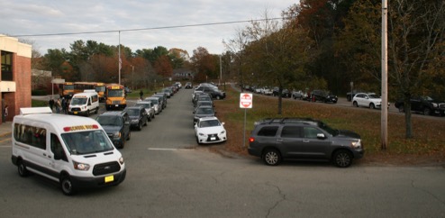 Vehicle Queues at Dismissal Time at the Hansen School
This figure is an image showing private autos and school buses in front of Hansen School. The school driveway, parking lot, and nearby street are all full of vehicles.